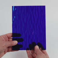 Video of the Mirrored Ink glass plate in iridescent ripple transparent blue, 15x19cm, held up and tilted to show its pattern and transparency