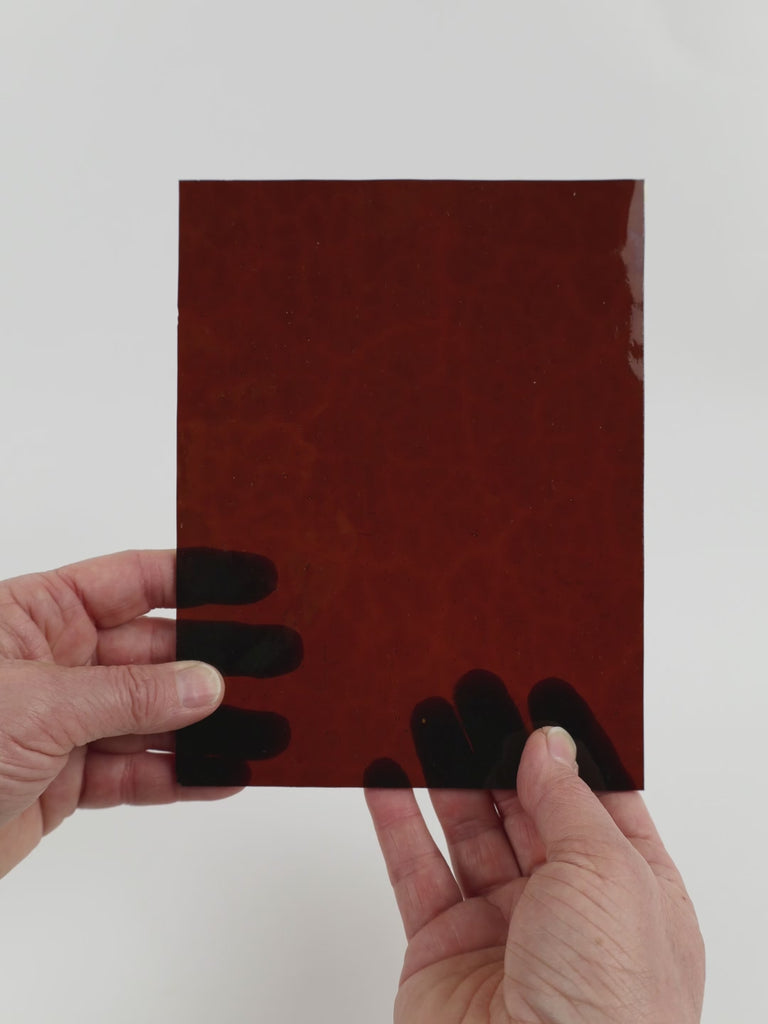 Video of the Brown Hammered glass plate in transparant brown, 15x19cm, held up and tilted to show its pattern and transparency