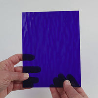 Video of the Deep Blue Ripple glass plate in ripple transparent blue, 15x19cm, held up and tilted to show its pattern and transparency