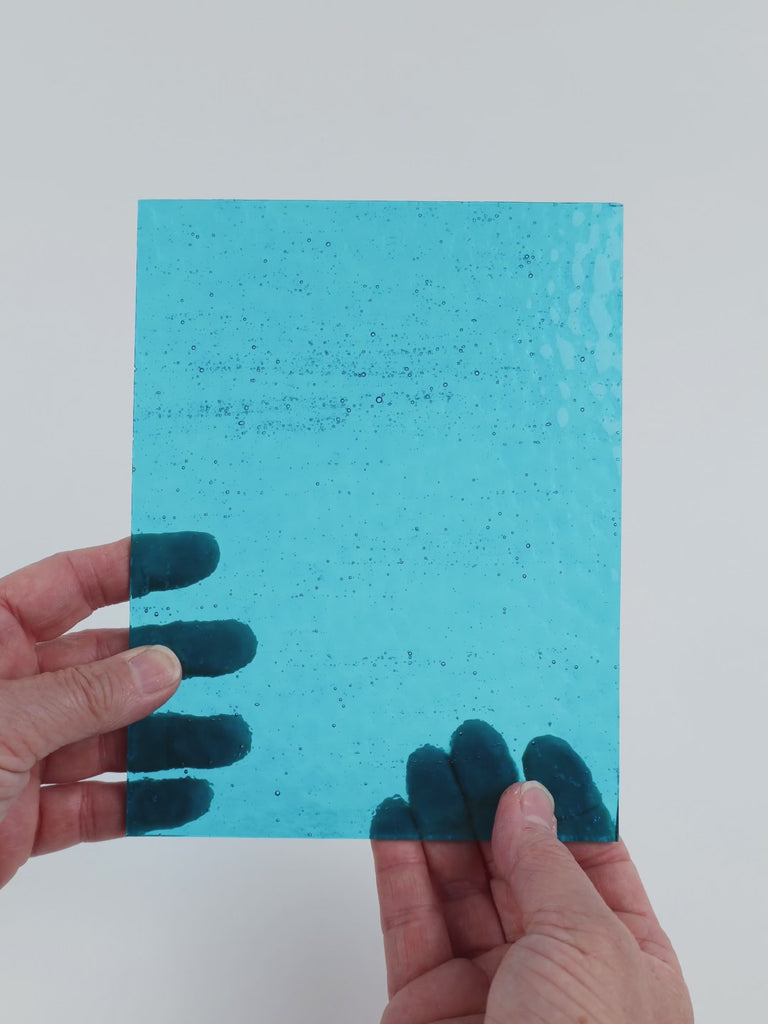 Video of the Pale Turquoise hammered glass plate in hammered transparent turquoise, 15x19cm, held up and tilted to show its pattern and transparency